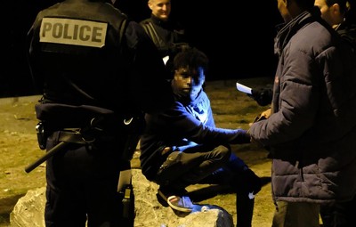 Des policiers effectuent des contrôles d’identité après avoir interrompu une distribution nocturne de nourriture, d’eau et de vêtements dans une zone industrielle de Calais, le 30 juin 2017, peu après minuit.  © 2017 Mail on Sunday/Philip Ide 