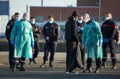 Des officiers de police et des professionnels de la santé interpellent un migrant à Calais (Pas-de-Calais), le 7 avril. BERNARD BARRON / AFP