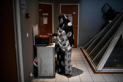 Une femme prépare un repas dans le couloir d’un immeuble de bureaux transformé en squat, à Vitry-sur-Seine, le 19 novembre 2021. CHRISTOPHE ARCHAMBAULT / AFP