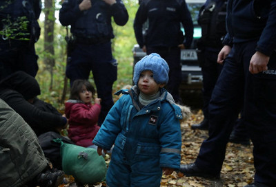 Un enfant migrant irakien entouré de garde-frontières et de policiers après avoir traversé avec sa famille la frontière biélorusse-polonaise, à Hajnowka, en Pologne, le 14 octobre 2021. Crédit : Reuters
