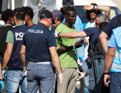 Migrants fouillés par des policiers italiens à leur débarquement sur le port de Pozzallo, en Sicile, le 7 juin. ANTONIO PARRINELLO / REUTERS