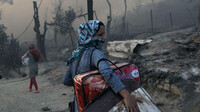 Une femme porte ses affaires après l'incendie du camp de Moria, sur l'île de Lesbos en 2020. Crédit : Reuters