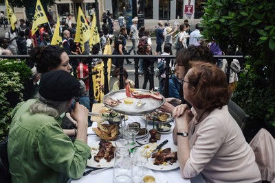 Une manifestation en faveur de la régularisation des sans-papiers passe devant la terrasse d’un restaurant, à Paris, le 2 juin. LUCAS BARIOULET / AFP