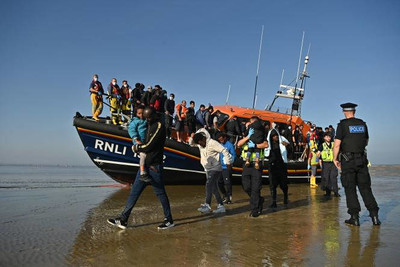Des migrants sont escortés par une équipe de sauveteurs de la Royal National Lifeboat Institution, à Dungeness, en Angleterre, le 7 septembre 2021. BEN STANSALL / AFP