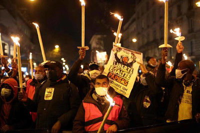 Des manifestants brandissent des bougies et des pancartes lors d’une manifestation pour la régularisation des sans-papiers, à l’occasion de la Journée internationale des migrants, le 18 décembre, à Paris. THOMAS COEX / AFP