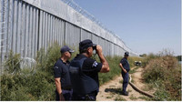 Des policiers patrouillent le long d'une clôture en acier construite près de la rivière Evros, le 22 août 2021. Crédit : EPA